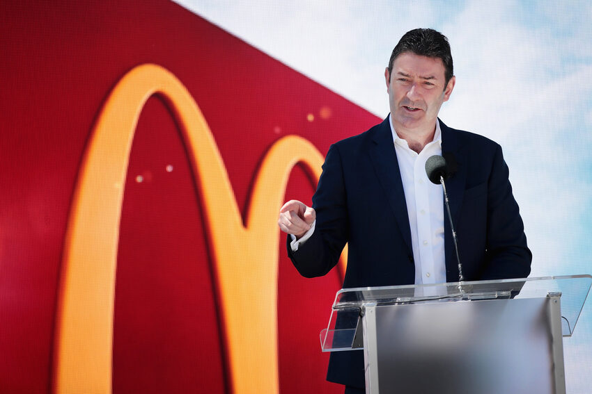 McDonald’s leader gesturing from the podium with the Golden Arches in the background